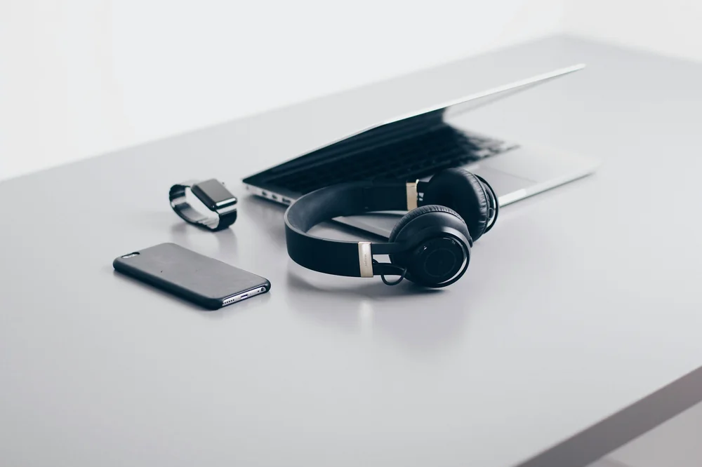 Casque audio, ordinateur portable et téléphone posés sur un bureau clair
