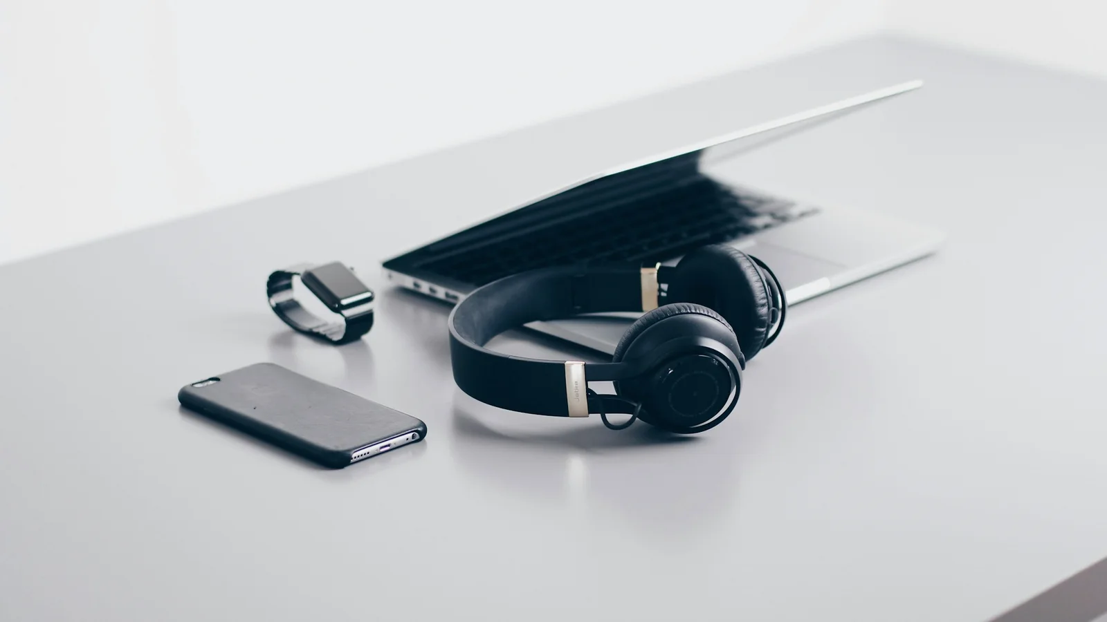 Casque audio, ordinateur portable et téléphone posés sur un bureau clair