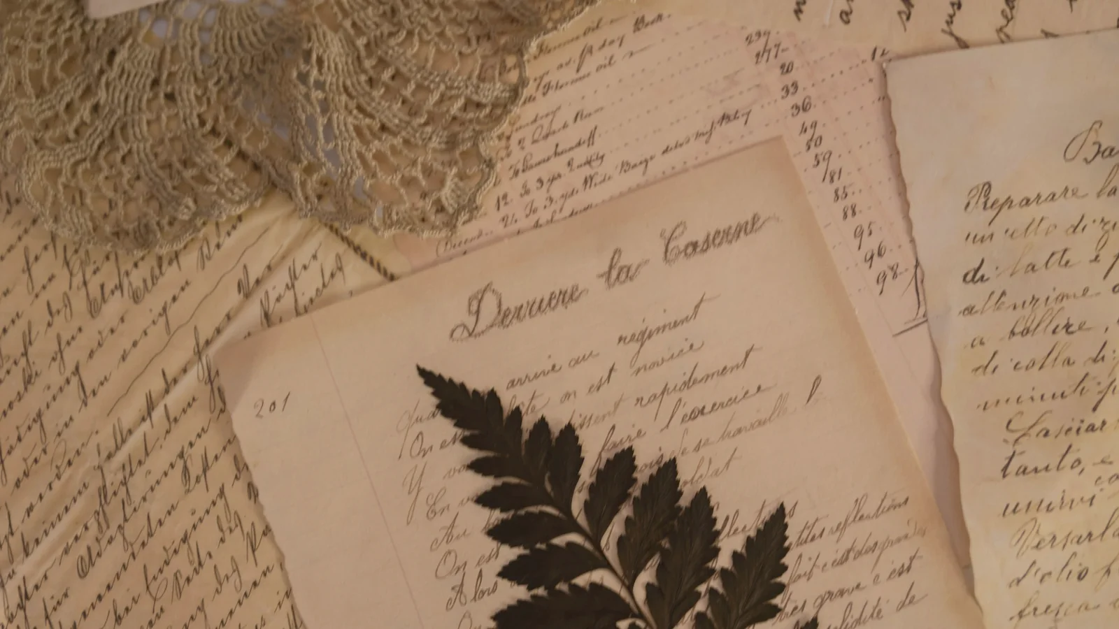 Lettres manuscrites jaunies, fougère séchée et petite flamme sur une table